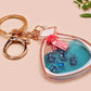 A large transparent acrylic shaker keychain with gold keyring, filled with mini chibi shrimps and labelled as emotional support shrimp