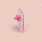 A clear acrylic pin badge with a pink heart-shaped pin back clasp. The design of the pin badge is of a cute chibi purple raccoon sat ona sofa wrapped in a blanket crying with the quote even baddies get saddies.