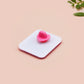 A clear acrylic pin badge with a pink heart-shaped pin back clasp. The design of the pin badge is of a cute chibi purple raccoon sat ona sofa wrapped in a blanket crying with the quote even baddies get saddies.