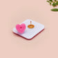 A clear acrylic pin badge with a pink heart-shaped pin back clasp. The design of the pin badge is of a cute chibi purple raccoon sat ona sofa wrapped in a blanket crying with the quote even baddies get saddies.