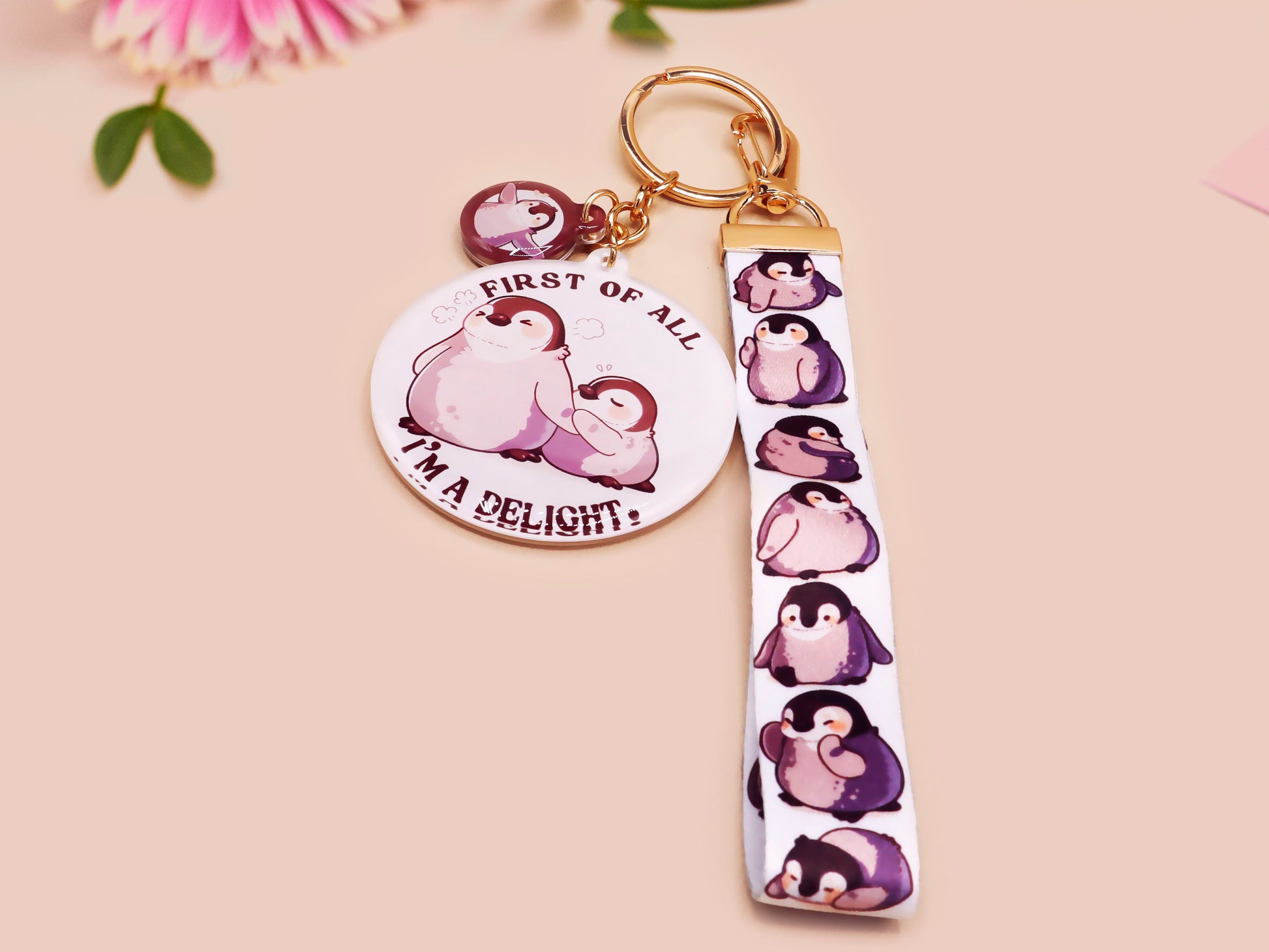 Acrylic epoxy baby penguin keychain with a large acrylic charm of two baby penguins with the quote first of all I'm a delight, a smaller charm of a cute penguin and a matching baby emperor penguin lanyard.