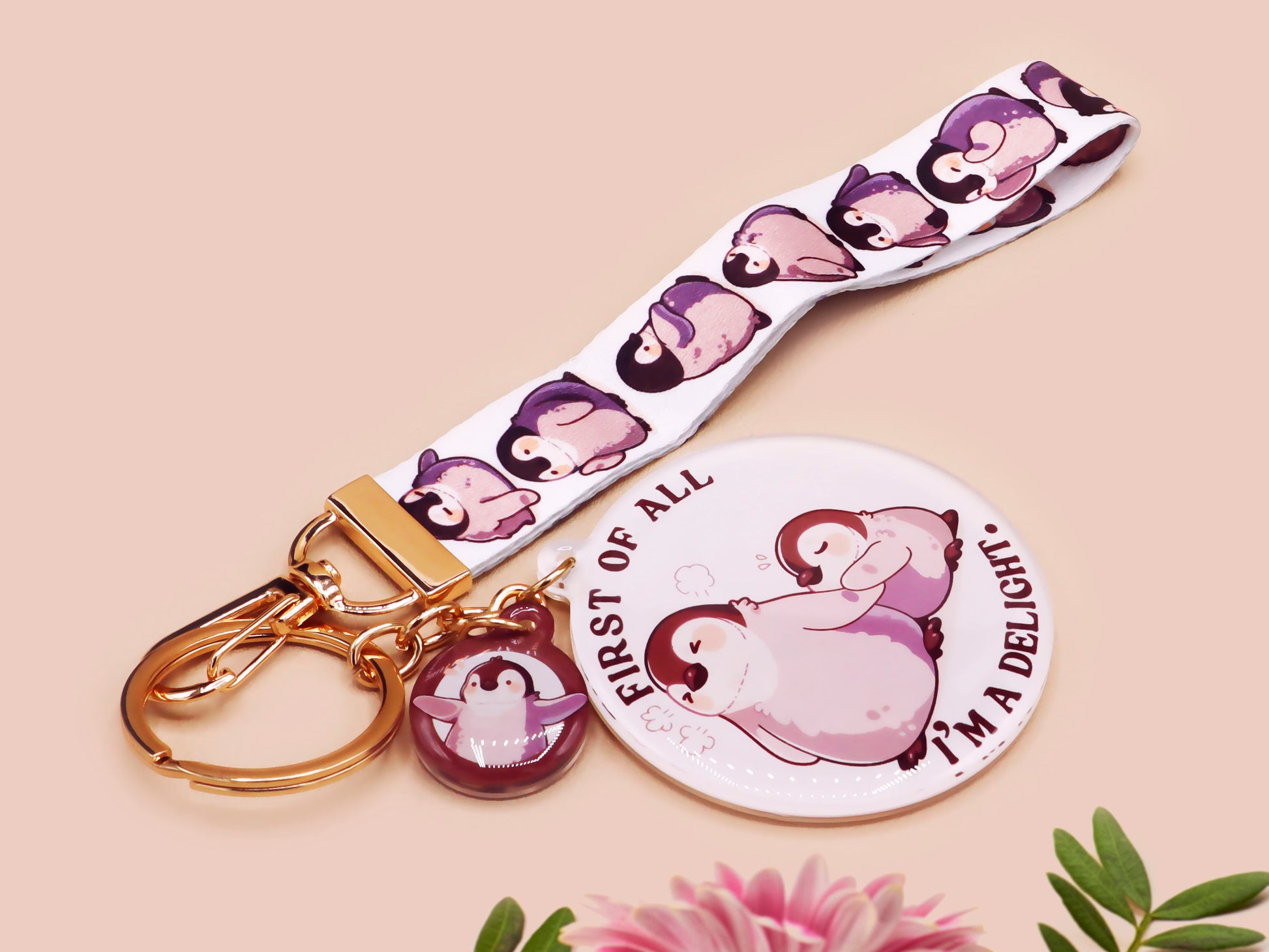 Acrylic epoxy baby penguin keychain with a large acrylic charm of two baby penguins with the quote first of all I'm a delight, a smaller charm of a cute penguin and a matching baby emperor penguin lanyard.