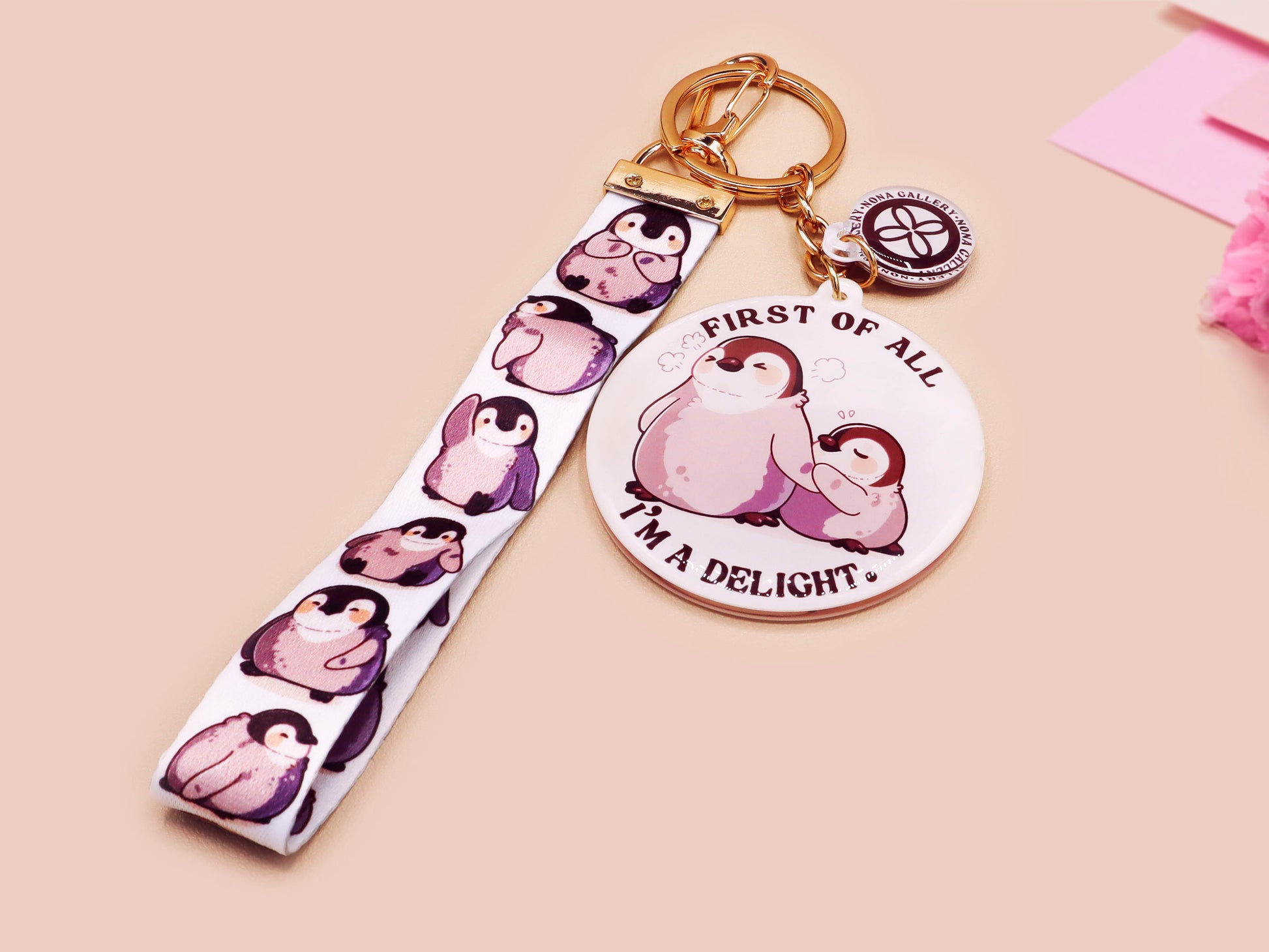 Acrylic epoxy baby penguin keychain with a large acrylic charm of two baby penguins with the quote first of all I'm a delight, a smaller charm of a cute penguin and a matching baby emperor penguin lanyard.