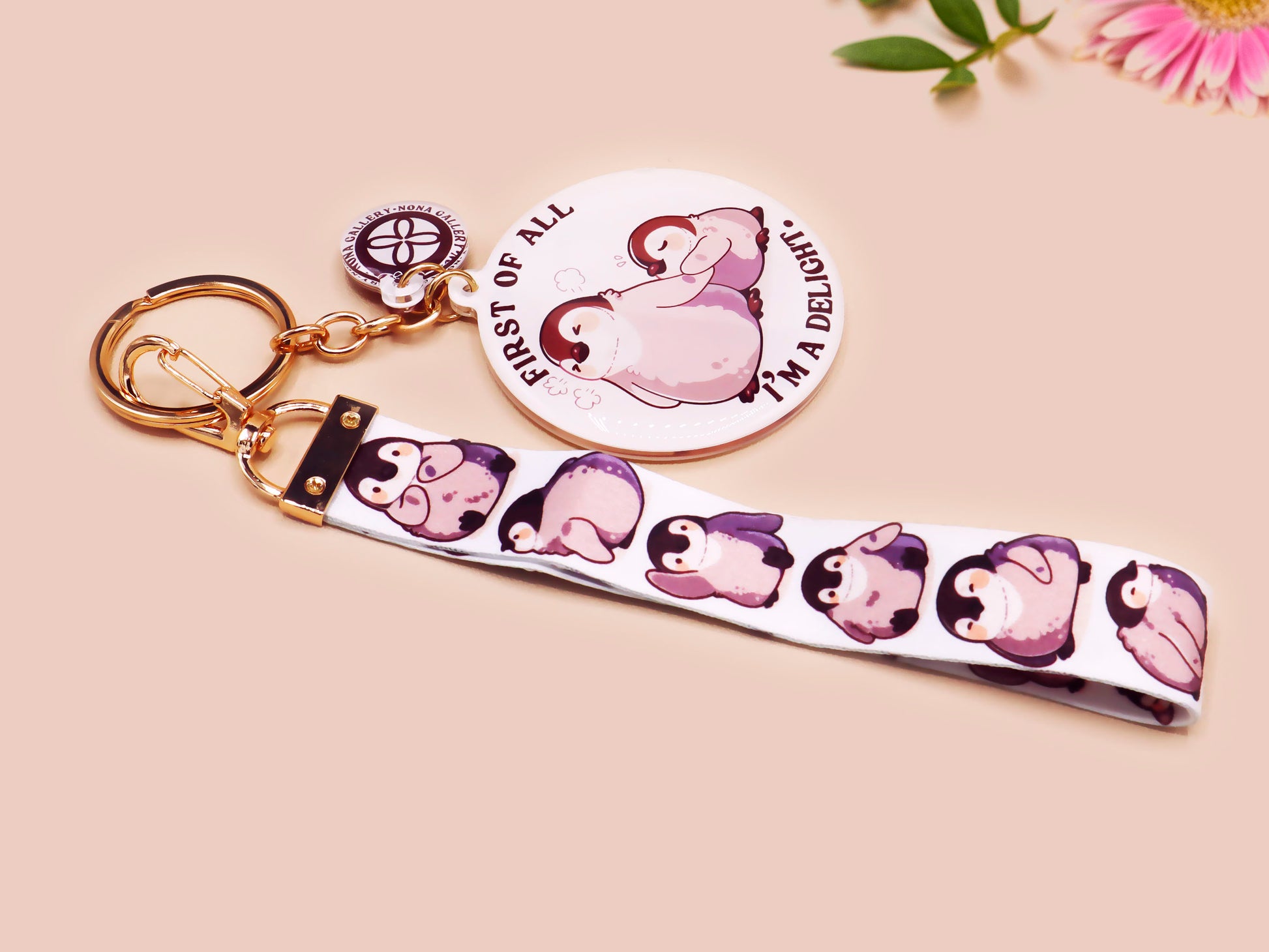 Acrylic epoxy baby penguin keychain with a large acrylic charm of two baby penguins with the quote first of all I'm a delight, a smaller charm of a cute penguin and a matching baby emperor penguin lanyard.