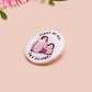 A clear acrylic pin badge with a pink heart-shaped pin back clasp. The design of the pin badge is of a cute baby penguin chicks squabbling with the quote first of all I'm a delight.