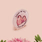 A clear acrylic pin badge with a pink heart-shaped pin back clasp. The design of the pin badge is of a cute baby penguin chicks squabbling with the quote first of all I'm a delight.