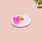 A clear acrylic pin badge with a pink heart-shaped pin back clasp. The design of the pin badge is of a cute baby penguin chicks squabbling with the quote first of all I'm a delight.