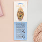 Gold Enamel Talisman Pin with yellow design and the words Baker's Talisman sits on a long white and blue backing card with gold accents. The backing card has details the symbolism of the different design elements of the Talisman pin.