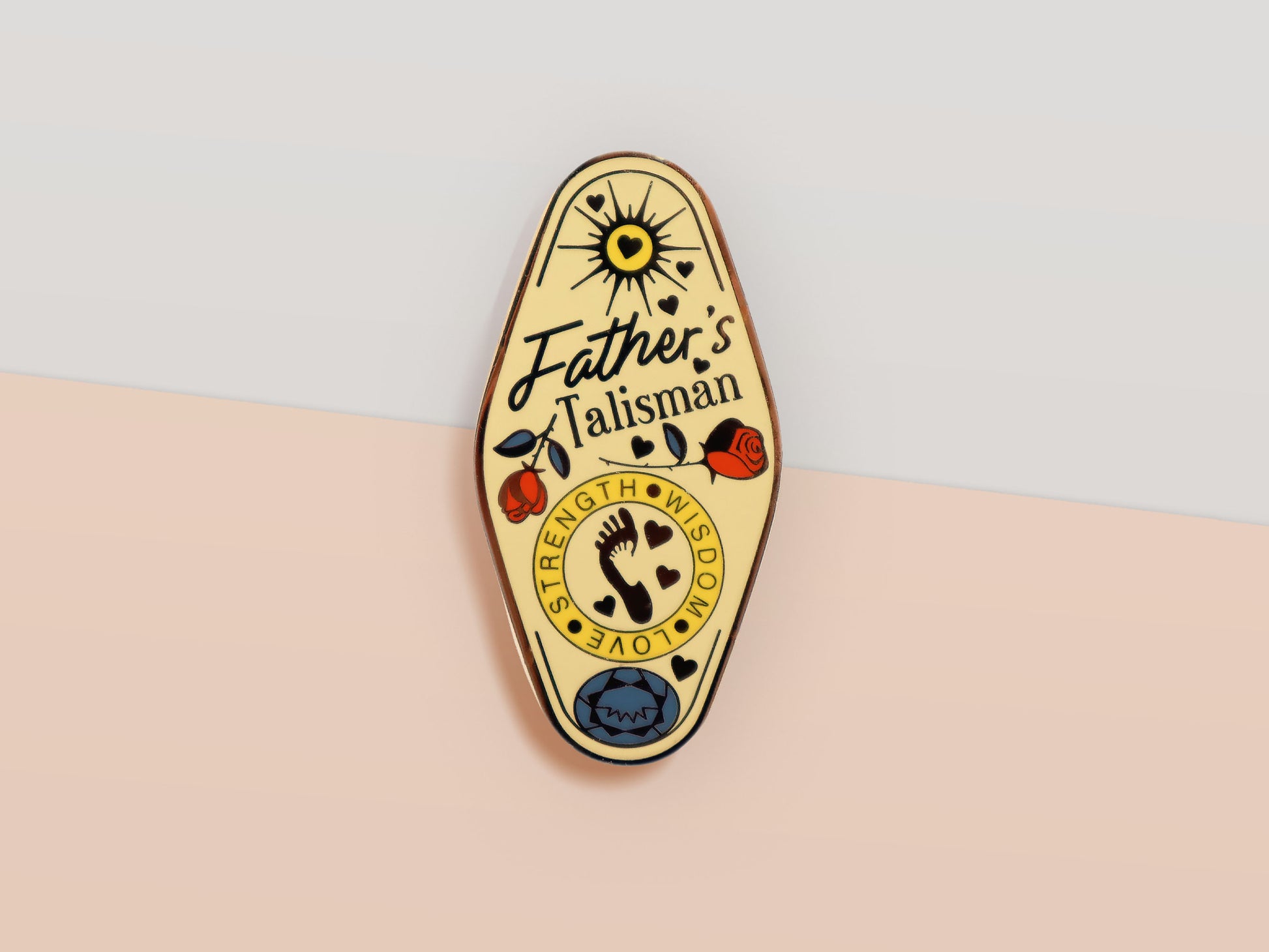 Gold Enamel Talisman Pin with yellow design and the words Father's Talisman, Strength Wisdom Love. The pins design includes a fathers and child's footprint, sunshine, hearts, as well as flowers and crystals.