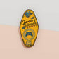 Gold Enamel Talisman Pin with yellow design and the words Gamer's Talisman, May Your Progress Always Save. The pins design includes a game console controller and health hearts, A jin Chan money toad, as well as plants and crystals.