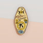 Gold Enamel Talisman Pin with yellow design and the words Mother's Talisman, Wisdom Love Strength. The pins design includes a a mother and child's hand, the three mothers moons, as well as flowers and crystals.