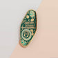 Gold Enamel Talisman Pin with blue design and the words Musician's Talisman, Ward of Musician's block. The pins design includes headphones and sheet music, raindrops, as well as flowers and crystals.