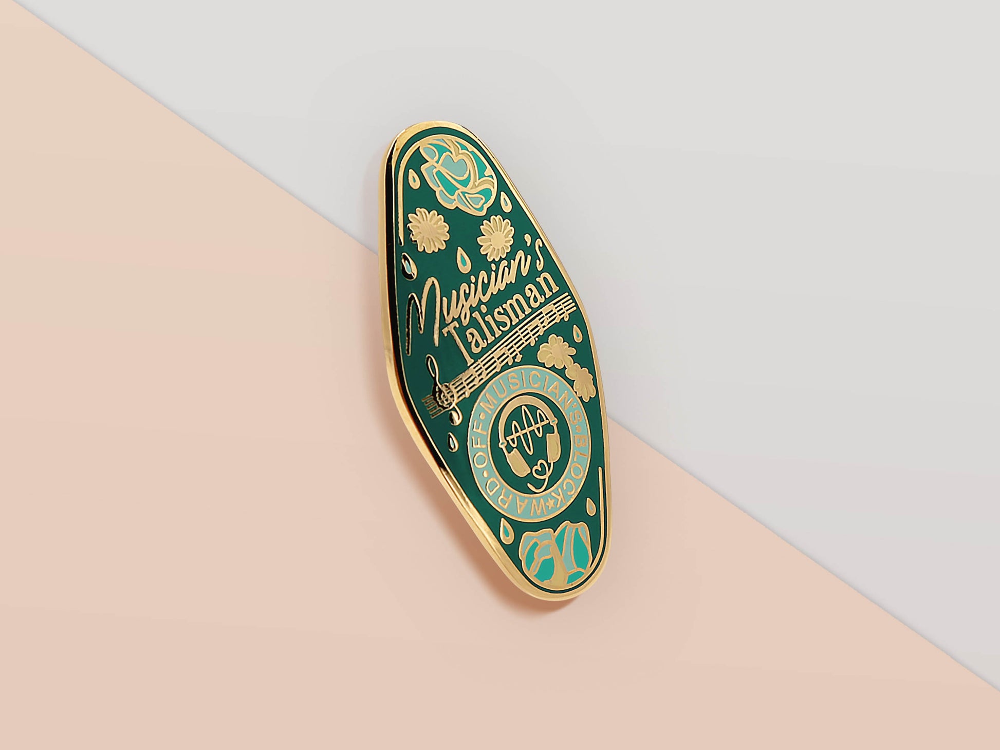 Gold Enamel Talisman Pin with blue design and the words Musician's Talisman, Ward of Musician's block. The pins design includes headphones and sheet music, raindrops, as well as flowers and crystals.
