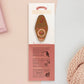 Gold Enamel Talisman Pin with brown design and the words Photographer's Talisman sits on a long white and red backing card with gold accents. The backing card has details the symbolism of the different design elements of the Talisman pin.
