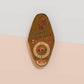 Gold Enamel Talisman Pin with brown design and the words Photographer's Talisman, Ward of bad lighting. The pins design includes a camera and a film, a red bird, as well as flowers and crystals.