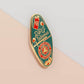 Gold Enamel Talisman Pin with red and blue design and the words RPG Talisman, Let Your Adventure Begin. The pins design includes a D20 dice and a sword and pencil, Hongbao red envelope, as well as acorns and crystals.
