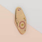 Gold Enamel Talisman Pin with white design and the words Student's Talisman, Ward of procrastination. The pins design includes a graduation cap and a rosette, a grass hopper, as well as plants and crystals.