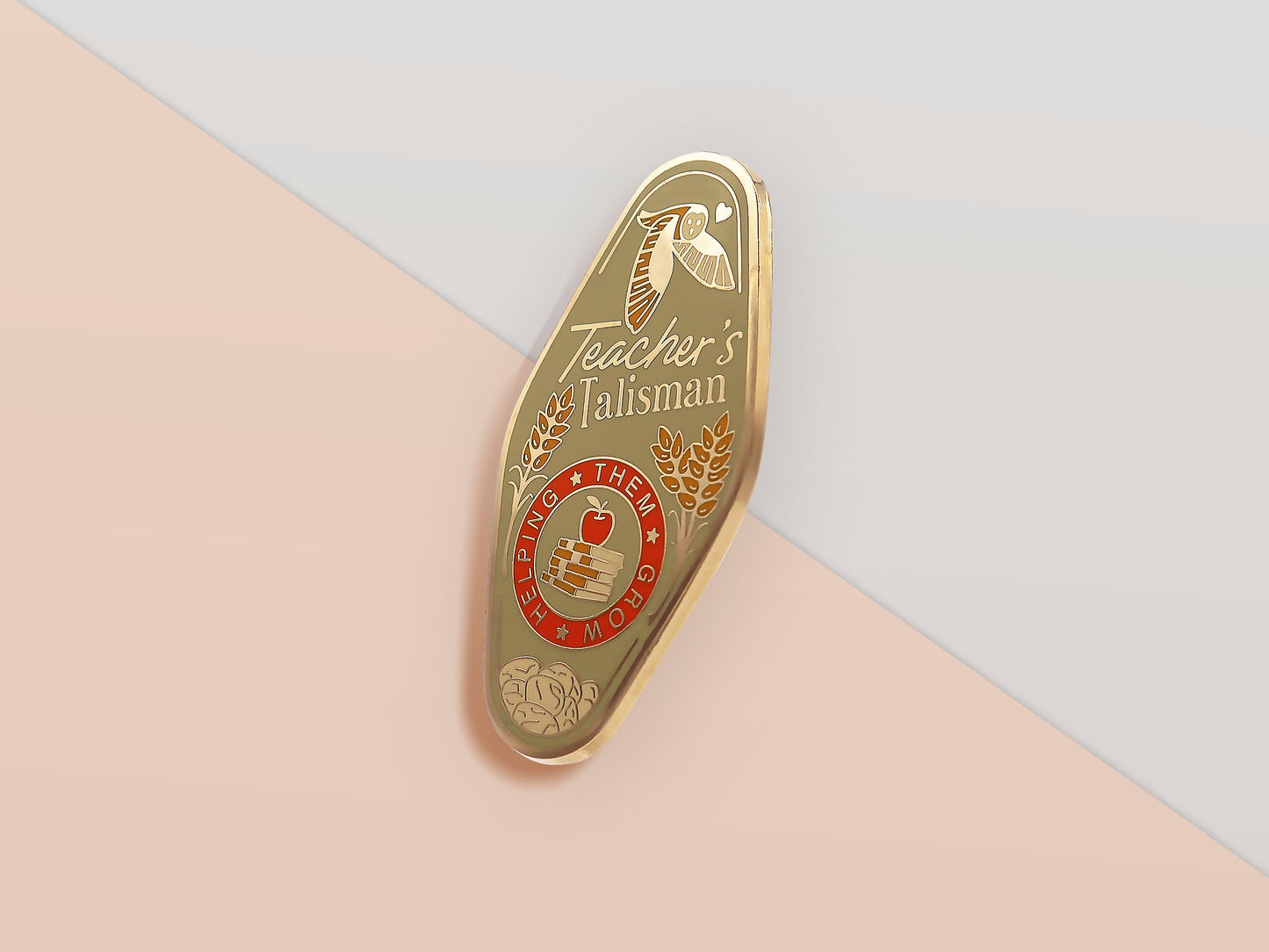 Gold Enamel Talisman Pin with green design and the words Teacher's Talisman, Helping Them Grow. The pins design includes a stack of books and an apple, a barn owl, as well as plants, flowers and crystals.