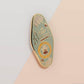 Gold Enamel Talisman Pin with blue design and the words Writer's Talisman, Ward of writer's block. The pins design includes a typewriter and a pen, snails, as well as keys and crystals.