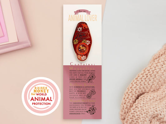 Gold Enamel Talisman Pin with red design and the words Animal Lover's Talisman sits on a long white and pink backing card with gold accents. The backing card has details the symbolism of the different design elements of the Talisman pin.