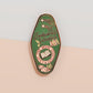A Bookworm's Talisman gold enamel pin on a gold foiled backing card that outlines the symbolism of the talisman including information and imagery on double shooting stars, sage leaves and brecciated jasper.