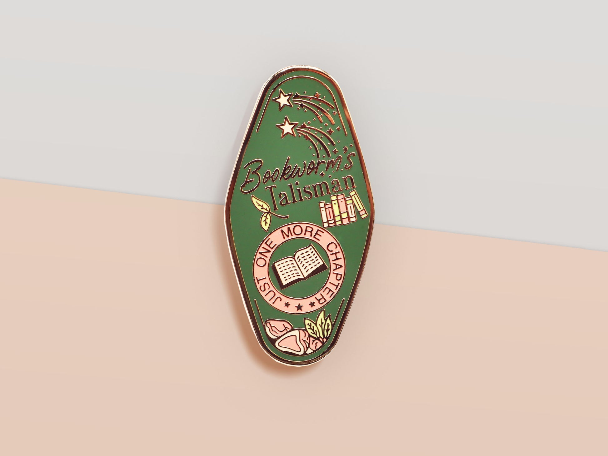 A Bookworm's Talisman gold enamel pin on a gold foiled backing card that outlines the symbolism of the talisman including information and imagery on double shooting stars, sage leaves and brecciated jasper.