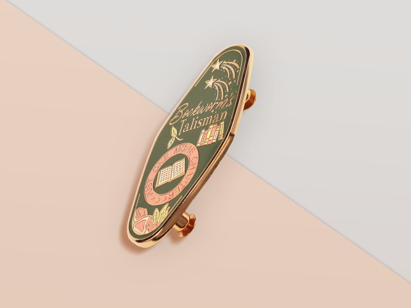 A Bookworm's Talisman gold enamel pin on a gold foiled backing card that outlines the symbolism of the talisman including information and imagery on double shooting stars, sage leaves and brecciated jasper.