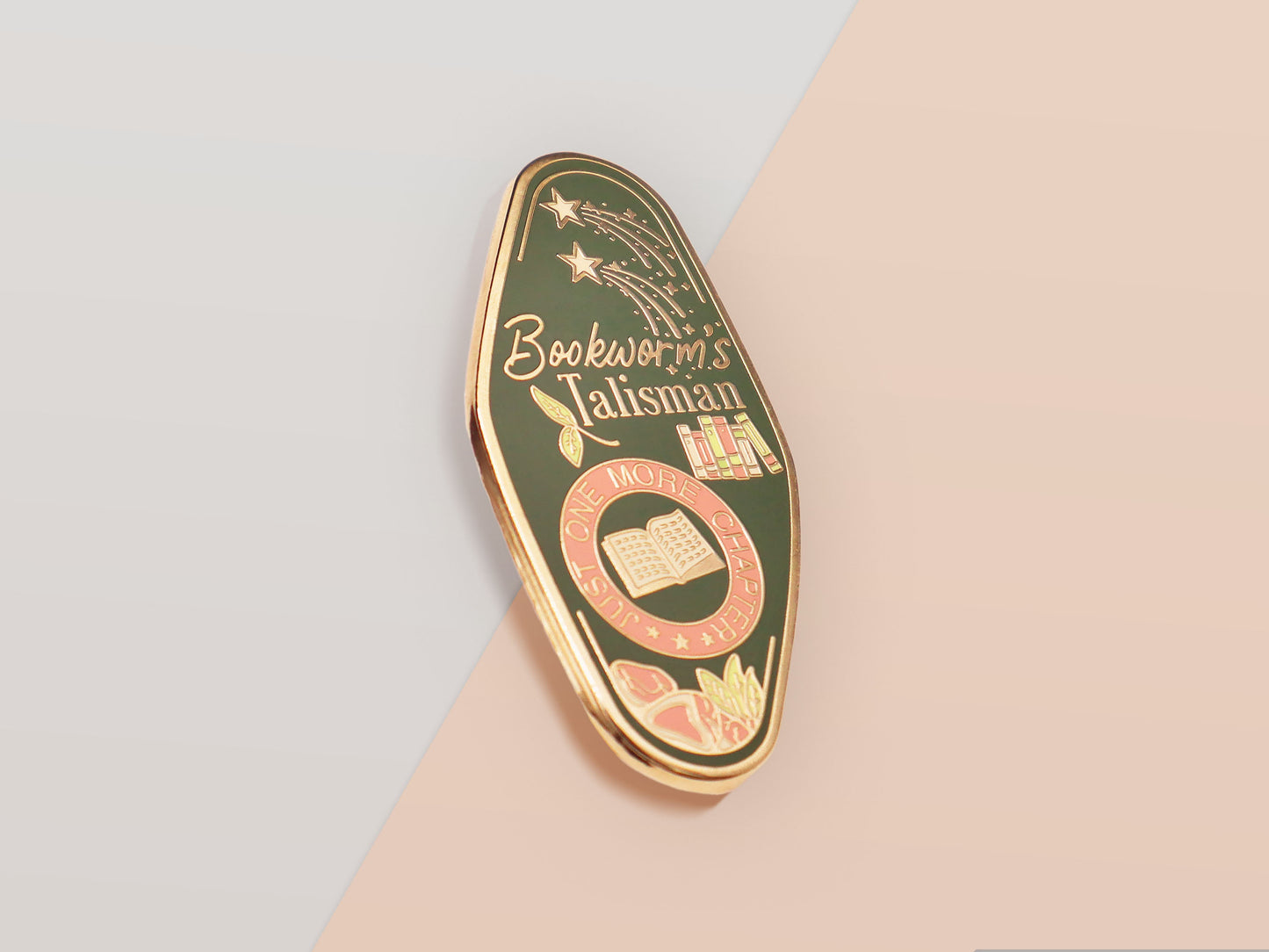 A Bookworm's Talisman gold enamel pin on a gold foiled backing card that outlines the symbolism of the talisman including information and imagery on double shooting stars, sage leaves and brecciated jasper.