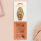 A Plant Person's Talisman gold enamel pin on a gold foiled backing card that outlines the symbolism of the talisman including information and imagery on sliced oranges, heather stems, and moss agate
