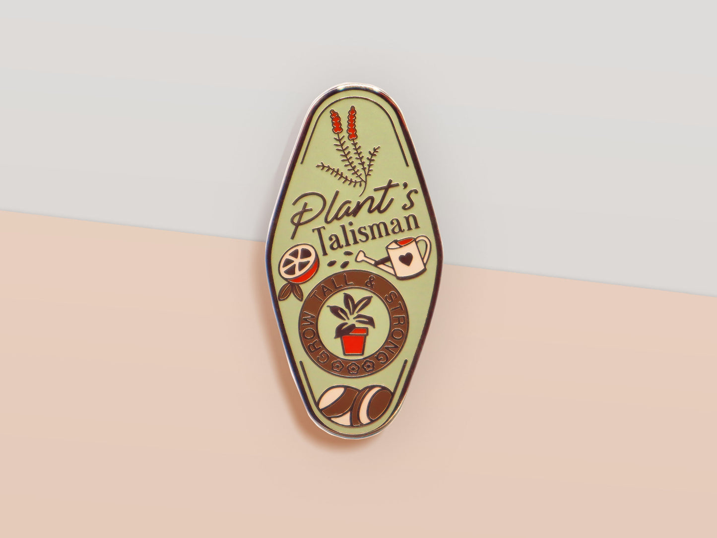 A Plant Person's Talisman gold enamel pin on a gold foiled backing card that outlines the symbolism of the talisman including information and imagery on sliced oranges, heather stems, and moss agate