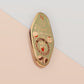 A Plant Person's Talisman gold enamel pin on a gold foiled backing card that outlines the symbolism of the talisman including information and imagery on sliced oranges, heather stems, and moss agate