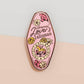 An Animal Lover's Talisman gold enamel pin on a gold foiled backing card that outlines the symbolism of the talisman including information and imagery on Magnolia flowers, yellow roses, and aragonite star clusters