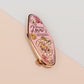 An Animal Lover's Talisman gold enamel pin on a gold foiled backing card that outlines the symbolism of the talisman including information and imagery on Magnolia flowers, yellow roses, and aragonite star clusters