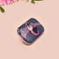 A clear acrylic pin badge with a pink heart-shaped pin back clasp. The design of the pin badge is of a cute chibi penguin dancing in a suit under a spotlight with the quote give 'em the ol' razzle dazzle