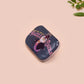 A clear acrylic pin badge with a pink heart-shaped pin back clasp. The design of the pin badge is of a cute chibi penguin dancing in a suit under a spotlight with the quote give 'em the ol' razzle dazzle