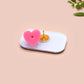 A clear acrylic pin badge with a pink heart-shaped pin back clasp. The design of the pin badge is of a cute chibi penguin dancing in a suit under a spotlight with the quote give 'em the ol' razzle dazzle