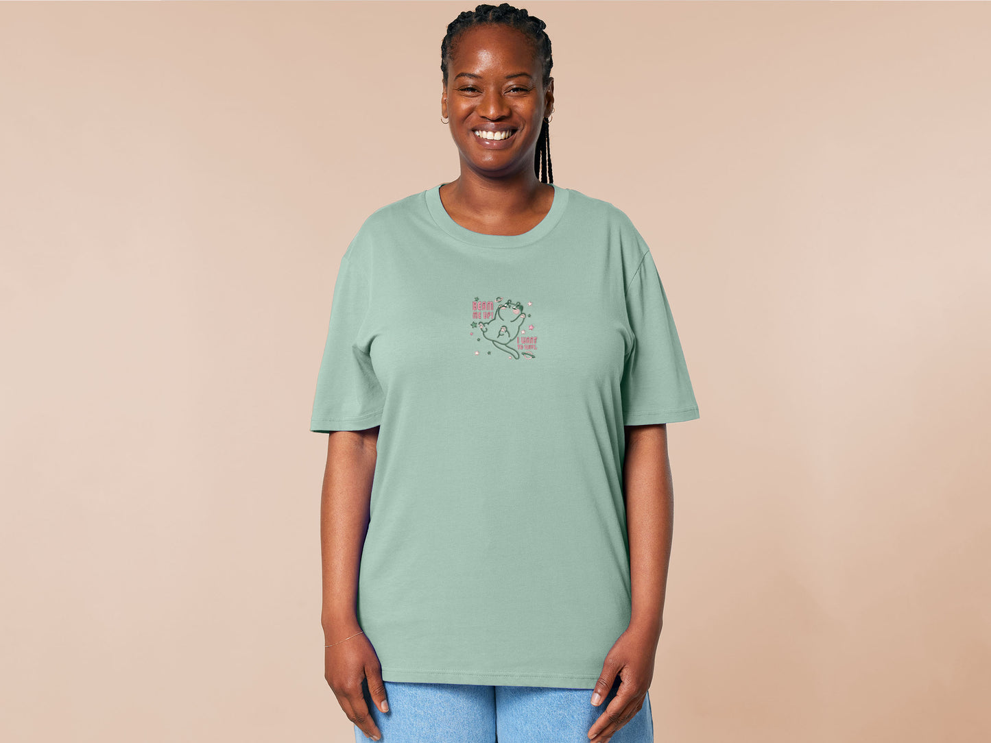 An embroidered green t-shirt design of a cute alien cat floating in space surrounded by stars and planets and by the quote beam me up! I want to leave