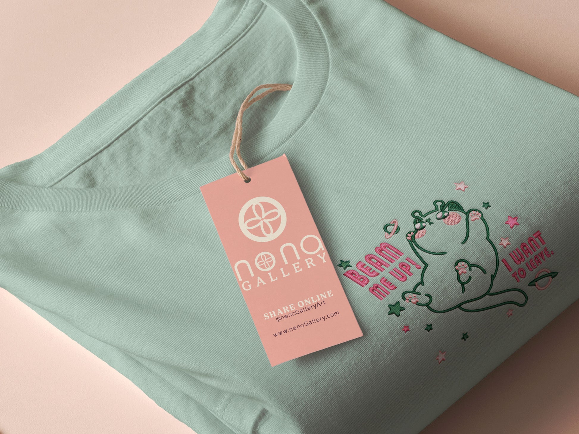 An embroidered green t-shirt design of a cute alien cat floating in space surrounded by stars and planets and by the quote beam me up! I want to leave