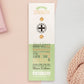 The Strength Talisman gold enamel pin on a gold foiled backing card that outlines the symbolism of the talisman including information and imagery on the Tabono adinkra Symbol, potential flowers, and chrysoprase stones
