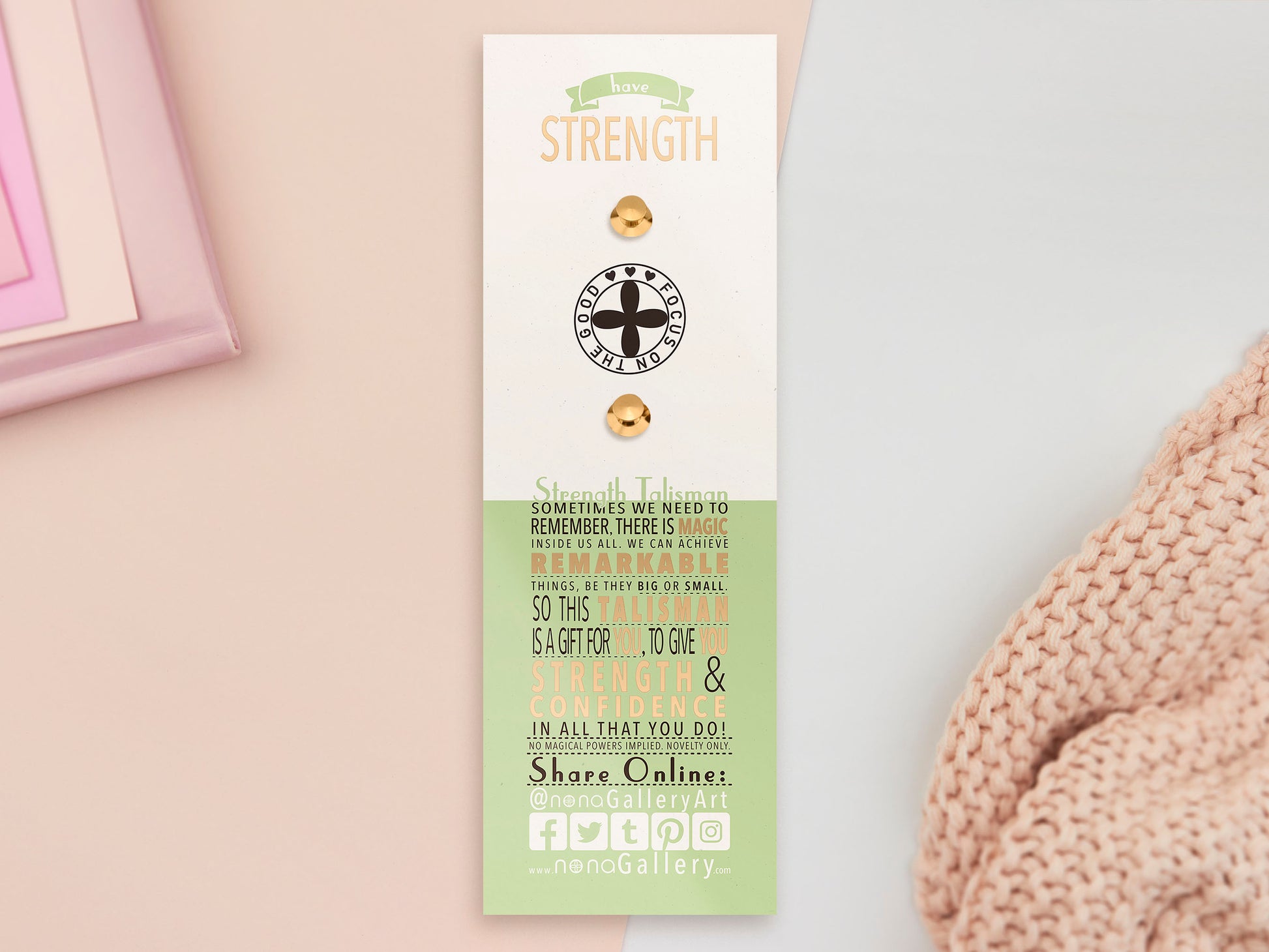 The Strength Talisman gold enamel pin on a gold foiled backing card that outlines the symbolism of the talisman including information and imagery on the Tabono adinkra Symbol, potential flowers, and chrysoprase stones