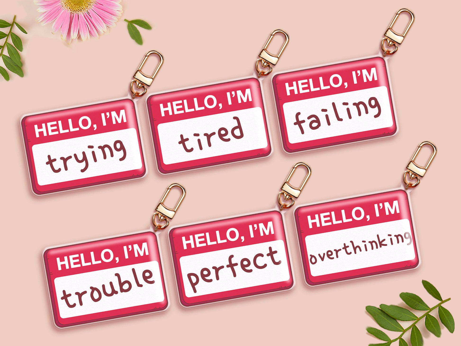Multiple acrylic keychains with gold swivel clasps in the hello I'm name badge style with multiple funny words such as trying, tired, failing, trouble, perfect, overthinking