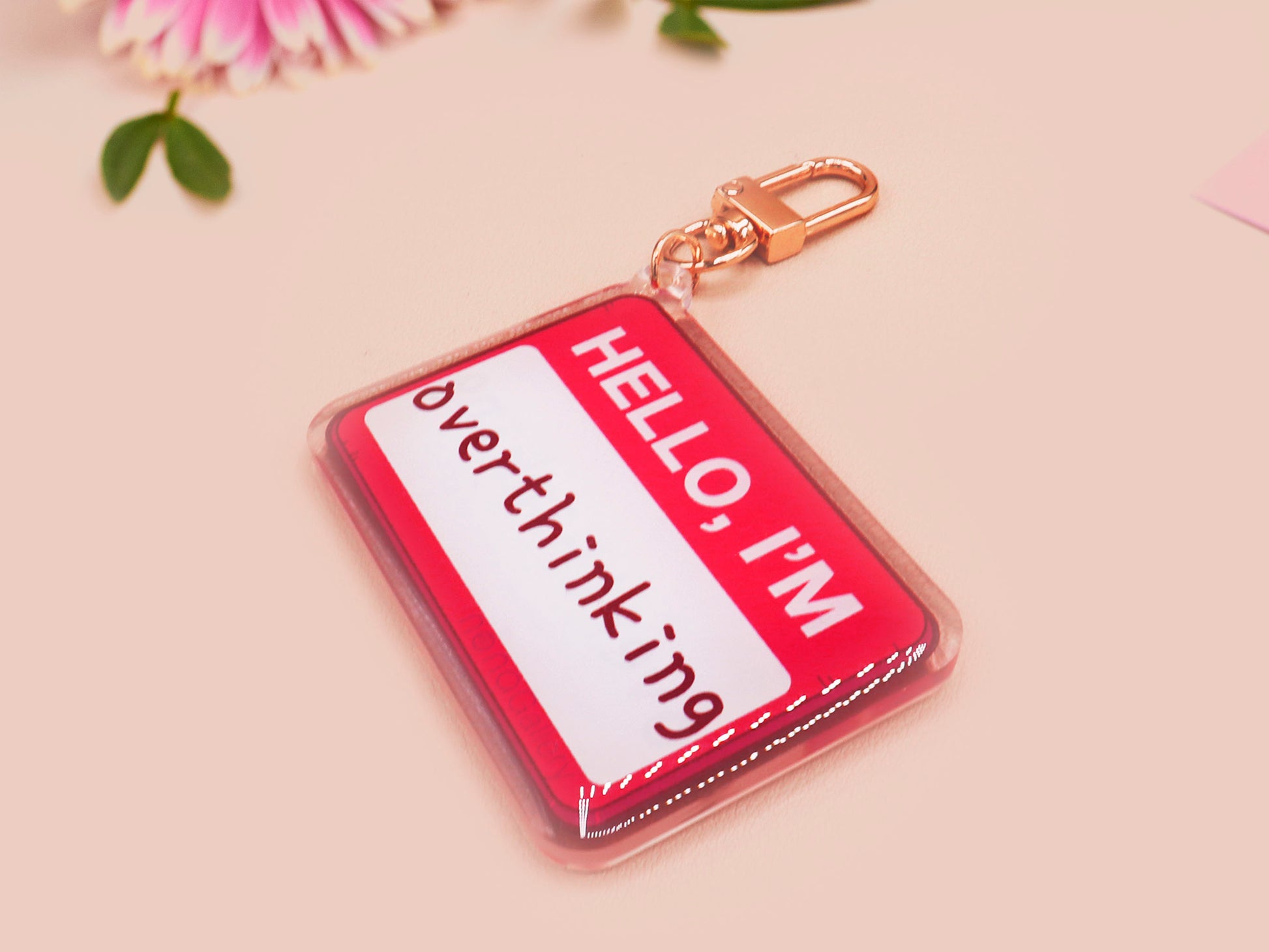Multiple acrylic keychains with gold swivel clasps in the hello I'm name badge style with the word overthinking written instead of a name