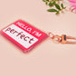 Multiple acrylic keychains with gold swivel clasps in the hello I'm name badge style with the word perfect written instead of a name