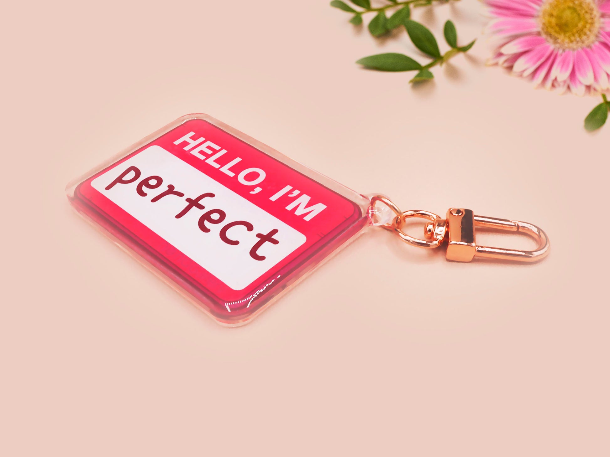 Multiple acrylic keychains with gold swivel clasps in the hello I'm name badge style with the word perfect written instead of a name