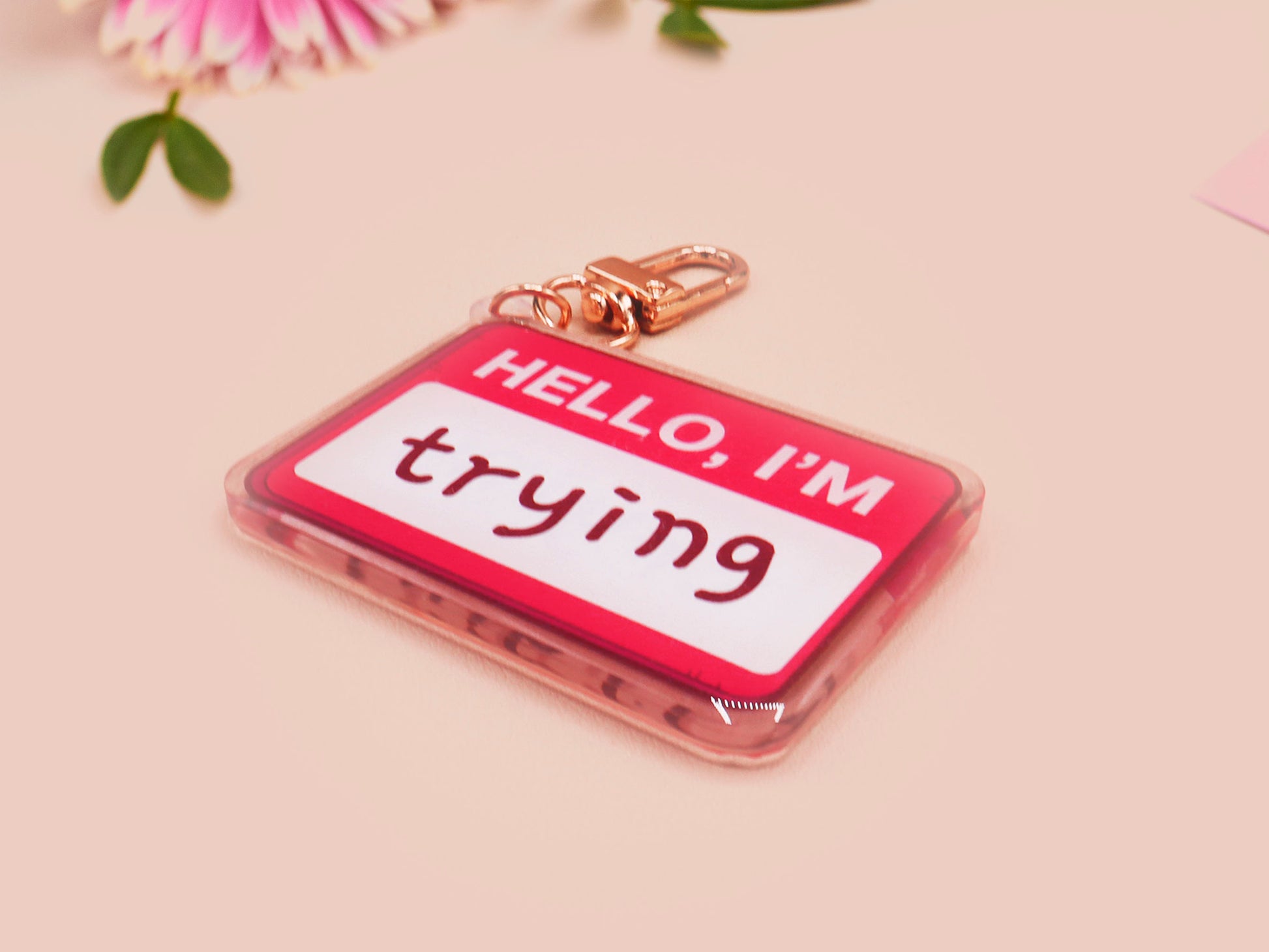 Multiple acrylic keychains with gold swivel clasps in the hello I'm name badge style with the word trying written instead of a name