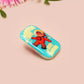 A clear acrylic pin badge with a pink heart-shaped pin back clasp. The design of the pin badge is of a cute chibi retro astronaut floating in sapce with the quote Houston I have so many problems