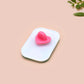 A clear acrylic pin badge with a pink heart-shaped pin back clasp. The design of the pin badge is of a cute chibi retro astronaut floating in sapce with the quote Houston I have so many problems