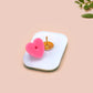 A clear acrylic pin badge with a pink heart-shaped pin back clasp. The design of the pin badge is of a cute chibi retro astronaut floating in sapce with the quote Houston I have so many problems