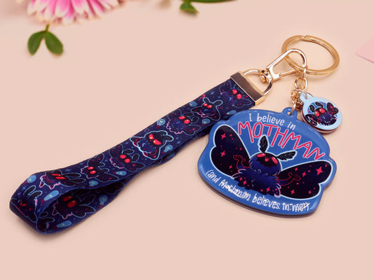 Acrylic epoxy Mothman Cryptid keychain with a large acrylic charm of a cute Mothman with the quote I believe in Mothman and Mothman belives in me, a smaller charm of a cute chibi Mothman and a matching Mothman lanyard.