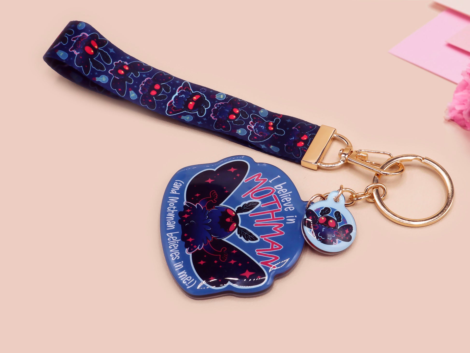 Acrylic epoxy Mothman Cryptid keychain with a large acrylic charm of a cute Mothman with the quote I believe in Mothman and Mothman belives in me, a smaller charm of a cute chibi Mothman and a matching Mothman lanyard.